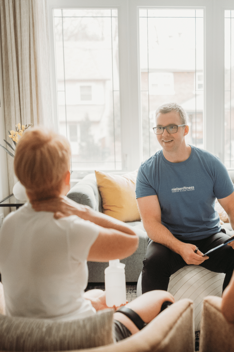 woman in white t-shirt consults with in-home personal trainer