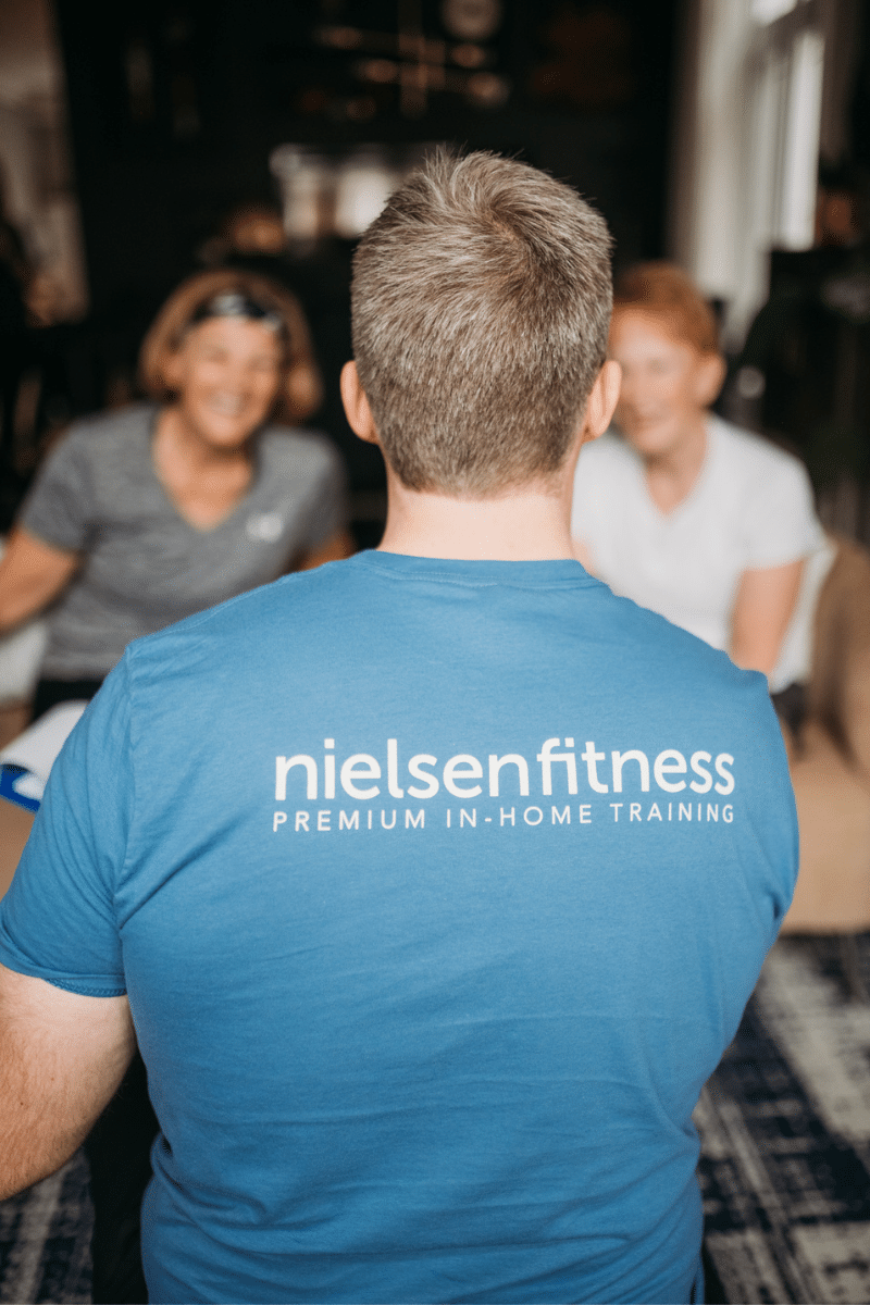 a trainer in a blue shirt instructs two fitness clients