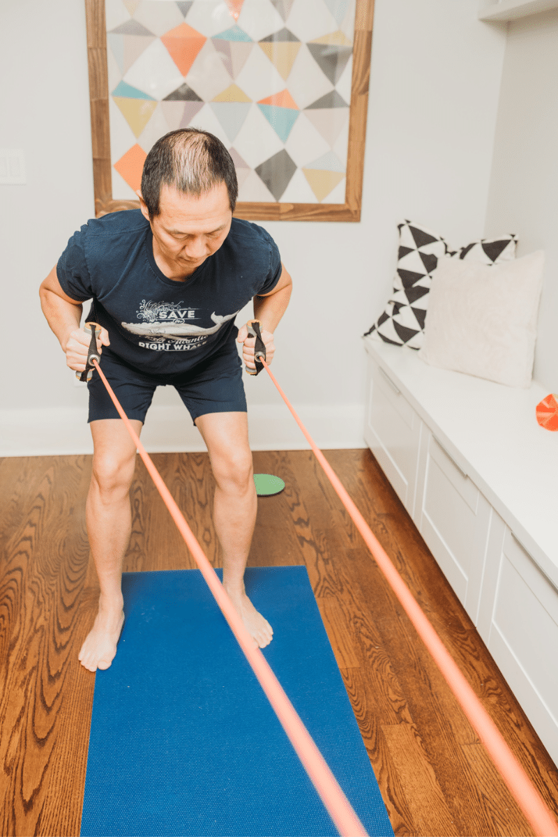 a man performs a bent over row with a resistance band