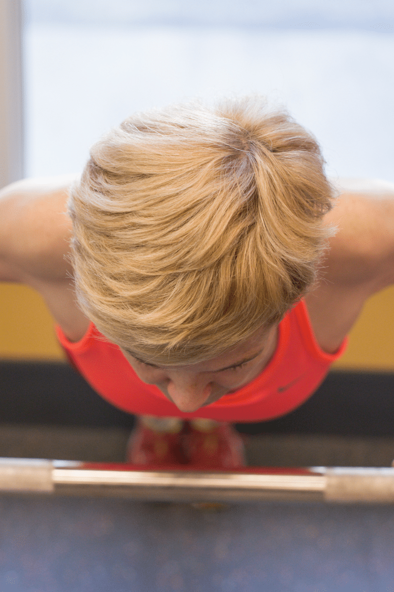 a woman with blonde hair does a push-up on a bar