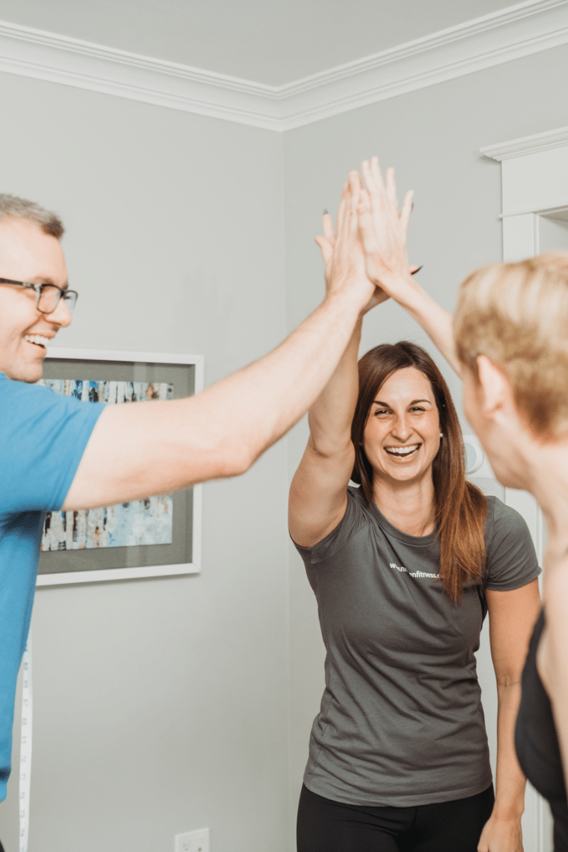 two trainers and a client do a triple high five