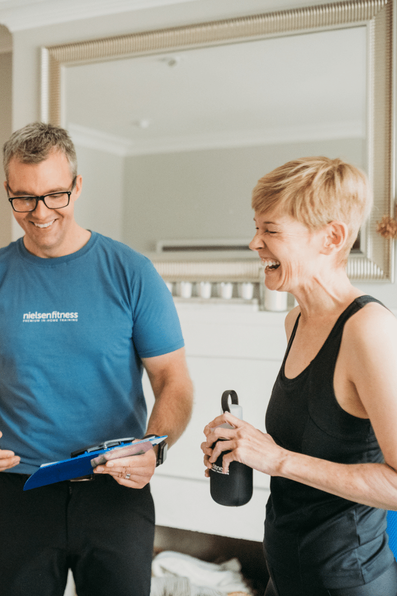 a health and fitness trainer laughs with a long-term client