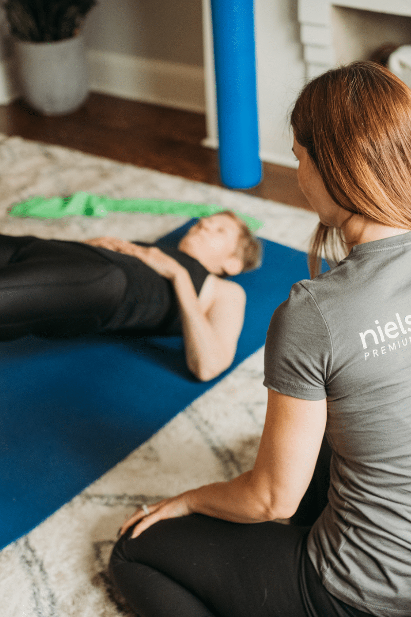 a personal trainer walks a client through a home workout on a mat