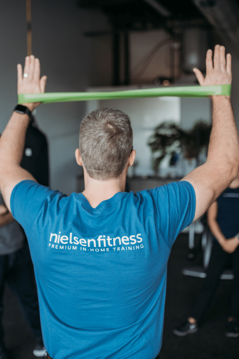 a trainer demonstrates using a looped band for supporting exercise